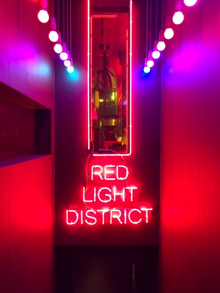 Picture of a neon sign readin "Red Light District" in what looks like a dimly red-lit corridor.